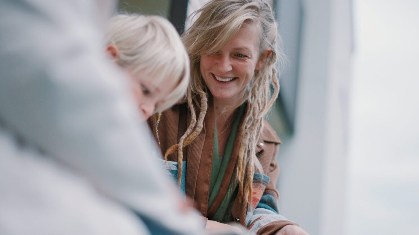 Junge Frau mit Rastafrisur schaut auf blonden Buben