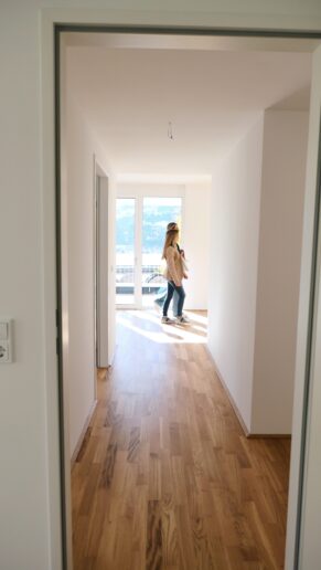 Immobilienberaterin geht mit Wohnungsinteressentin durch den Raum