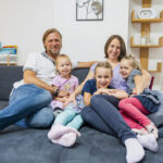 Familie auf Couch, Eltern mit drei Mädchen