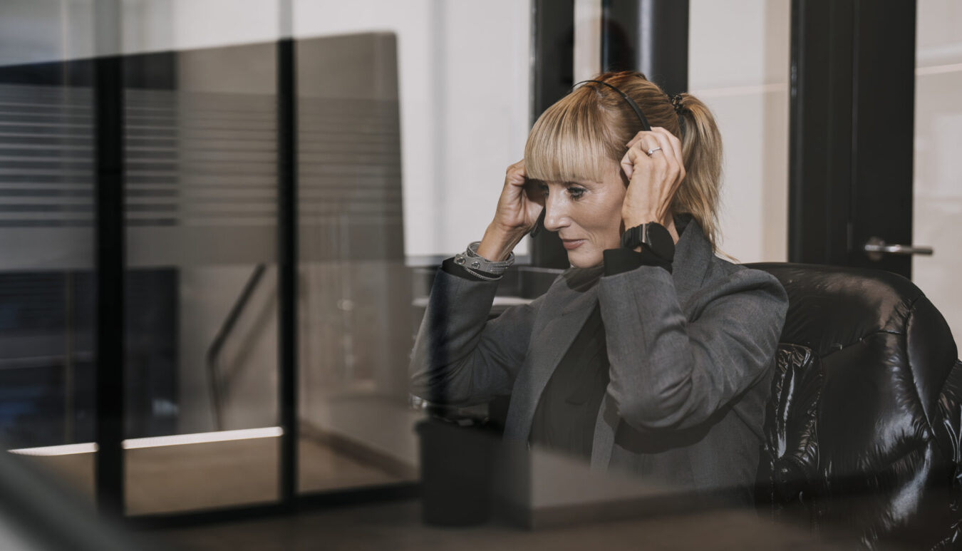 Eine Blonde Dame mit zusammengebundenen Haaren und Headset