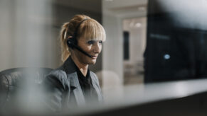 Eine Blonde Dame mit zusammengebundenen Haaren und Headset