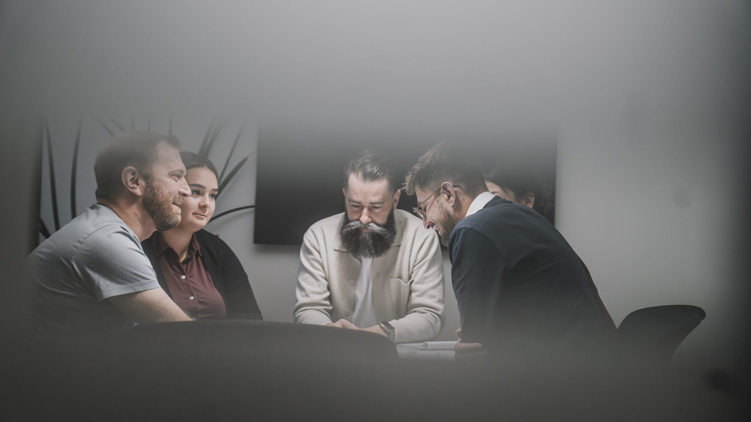 Meeting mit mehreren PErsonen, eien blonde junge Frau, ein Mann mit Bart in der Mitte und eine weiter Frau auf der anderen Seite