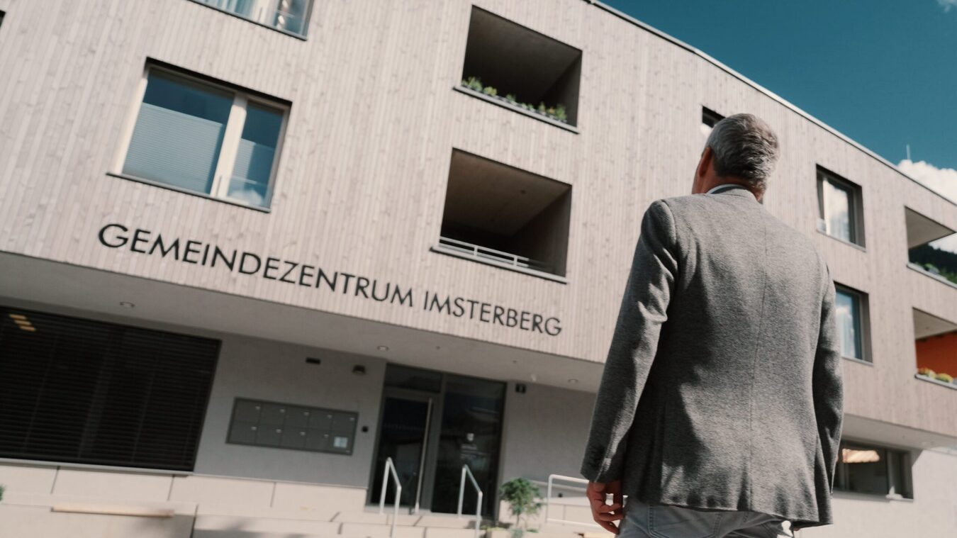 Vorderansicht des Gemeindeamtes in Imsterberg, Bürgermeister schaut auf den Eingang