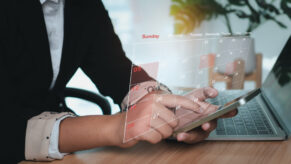 am Handy, Hände tippen in das Handy, virtueller Terminplan im Vordergrund