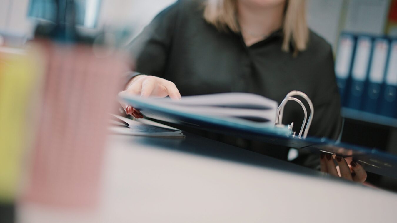 Eine blonde Frau blättert in Ordner