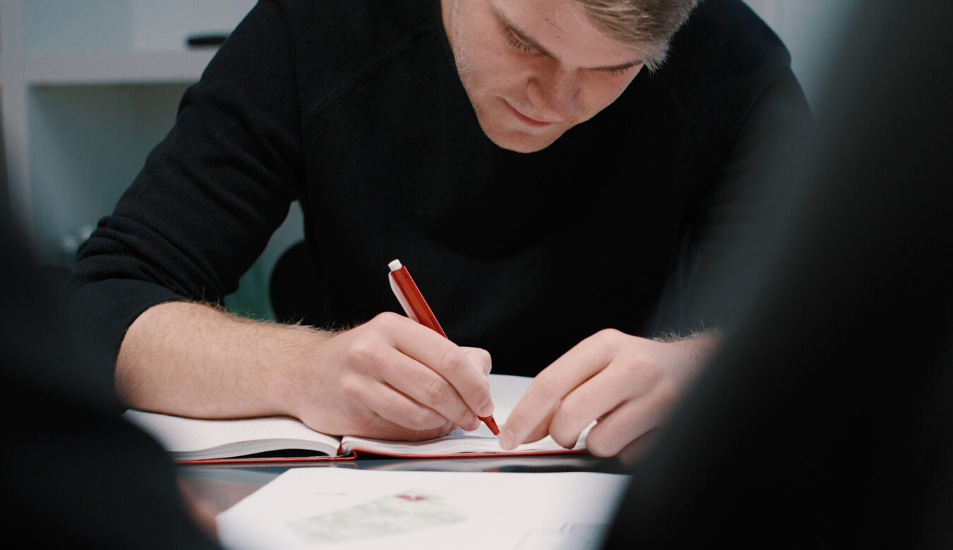 Ein junger Mann notiert etwas auf einem Schriftstück