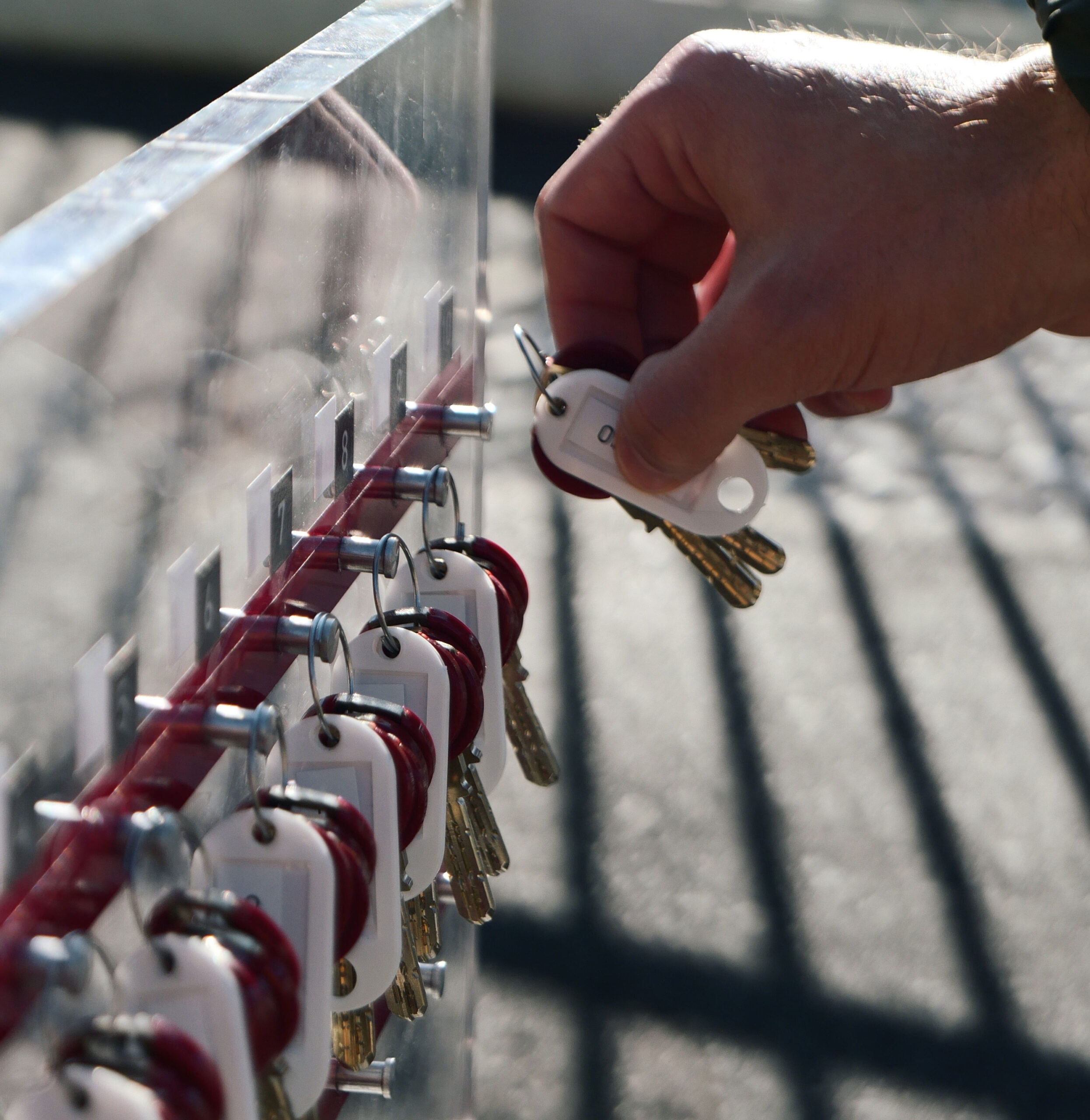 Situation Wohnungsübergabe: Ein Hand nimmt Wohnungsschlüssel vom Schlüsselboard